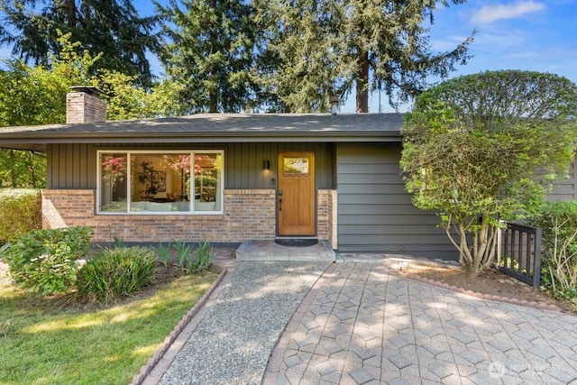 view of front of home with a chimney and brick siding