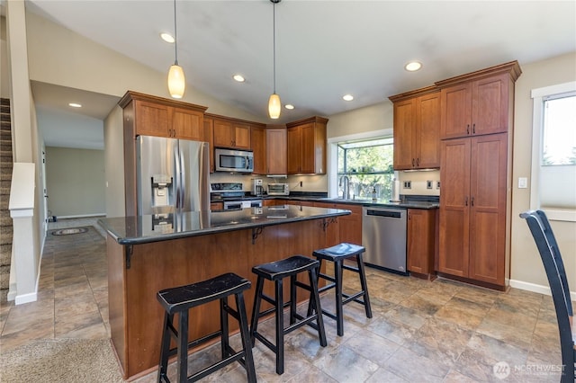kitchen featuring appliances with stainless steel finishes, dark countertops, a kitchen island, recessed lighting, and decorative light fixtures