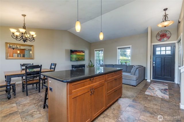 kitchen with vaulted ceiling, stone finish floors, a chandelier, baseboards, and a center island