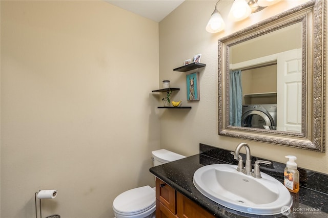 bathroom featuring toilet, vanity, and washing machine and dryer