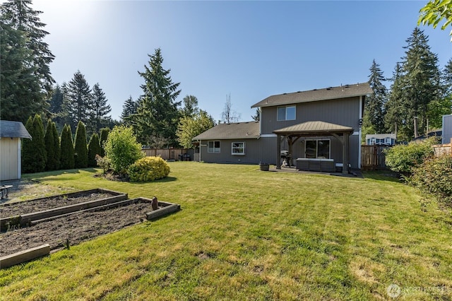 back of house featuring a vegetable garden, a gazebo, and a hot tub