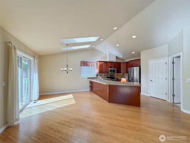 kitchen featuring appliances with stainless steel finishes, a chandelier, a peninsula, a skylight, and light wood finished floors