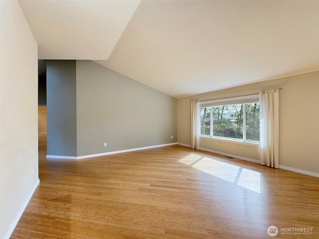 unfurnished room with light wood finished floors, baseboards, and lofted ceiling