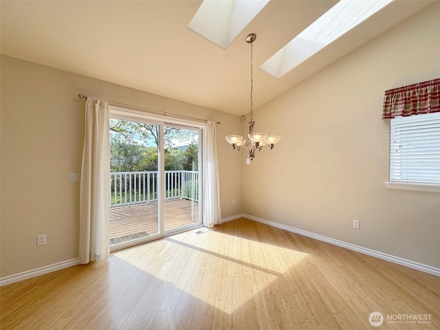 spare room featuring a skylight, light wood finished floors, a chandelier, baseboards, and vaulted ceiling