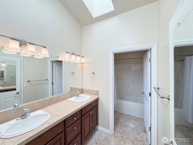 bathroom with a skylight, double vanity, and high vaulted ceiling