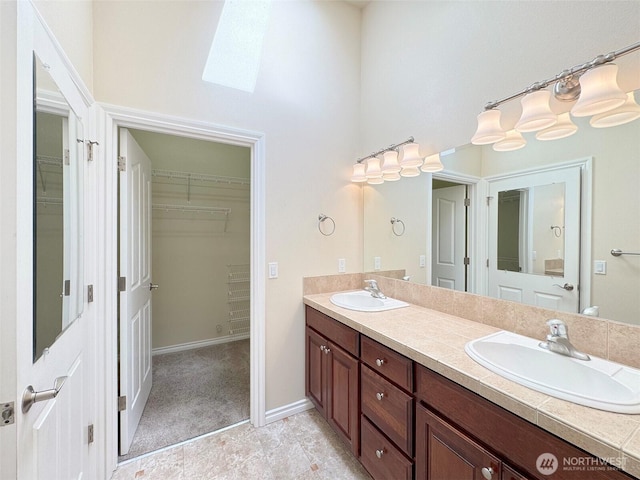 bathroom featuring a skylight, double vanity, a spacious closet, and a high ceiling