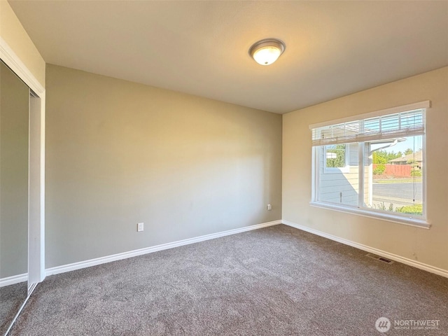 unfurnished room with dark colored carpet and baseboards