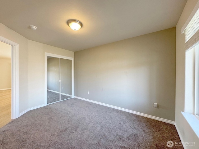 unfurnished bedroom with carpet, a closet, and baseboards