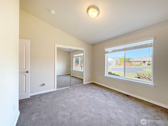 unfurnished bedroom with carpet, lofted ceiling, baseboards, and a closet
