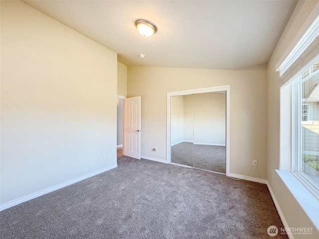 unfurnished bedroom with carpet flooring, lofted ceiling, baseboards, and a closet
