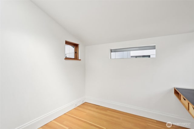 additional living space featuring light wood-type flooring, baseboards, plenty of natural light, and lofted ceiling