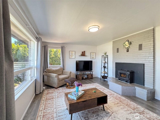 living room featuring wood finished floors, baseboards, and a wood stove