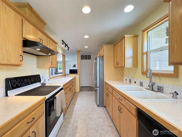 kitchen with electric stove, freestanding refrigerator, under cabinet range hood, a sink, and dishwasher