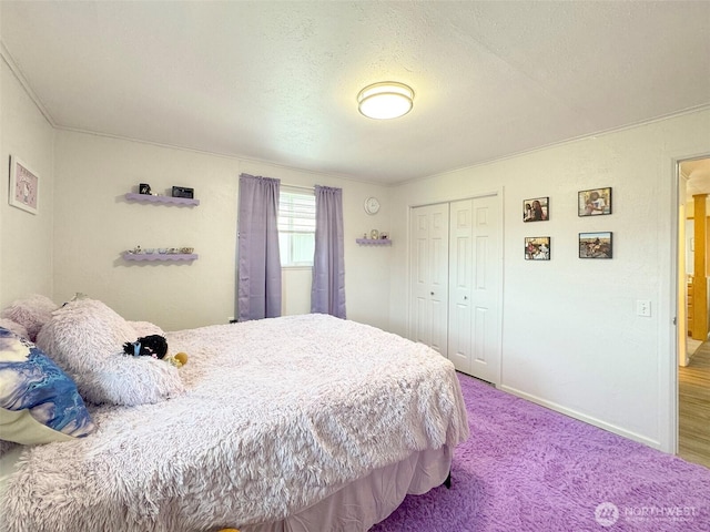 carpeted bedroom with a closet, baseboards, and a textured ceiling