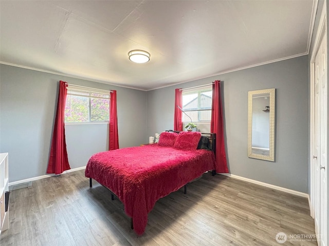 bedroom featuring wood finished floors, multiple windows, baseboards, and crown molding
