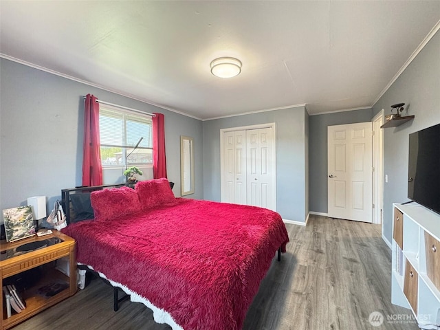 bedroom with wood finished floors, ornamental molding, a closet, and baseboards