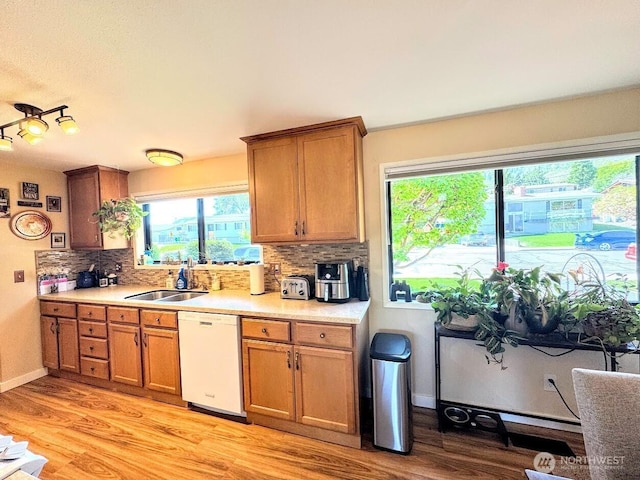 kitchen with dishwasher, backsplash, light wood-style floors, light countertops, and brown cabinets