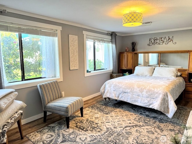 bedroom featuring baseboards, wood finished floors, and crown molding
