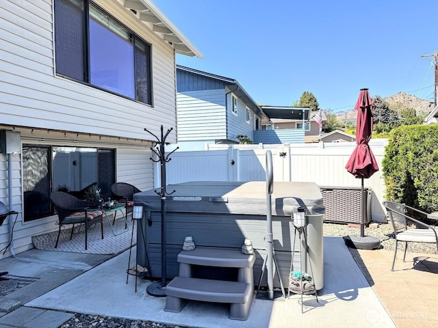 view of patio / terrace featuring a hot tub and fence