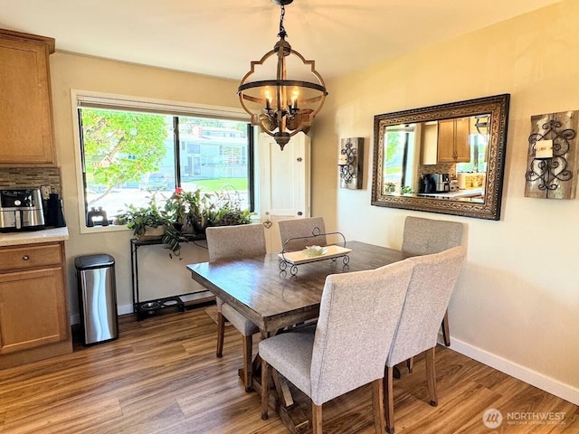 dining area with a chandelier, light wood-style flooring, and baseboards