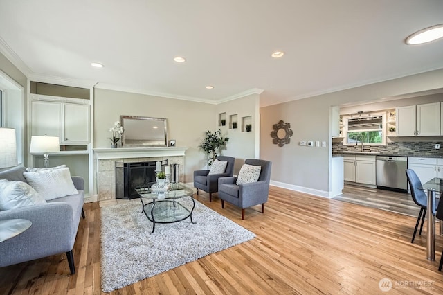 living room featuring ornamental molding, light wood finished floors, a tile fireplace, baseboards, and recessed lighting