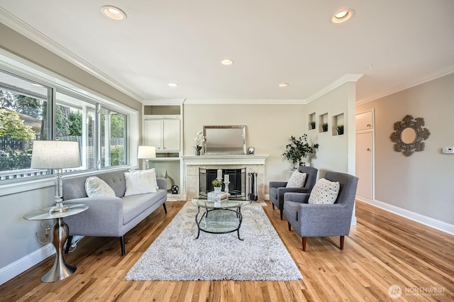 living room featuring ornamental molding, light wood finished floors, a fireplace, baseboards, and recessed lighting