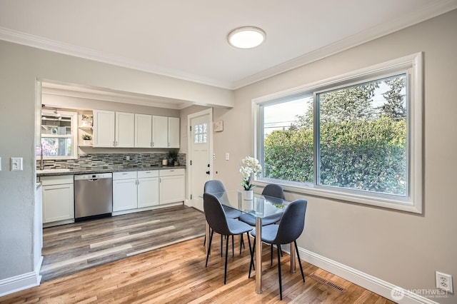 dining space with crown molding, light wood-style flooring, and baseboards