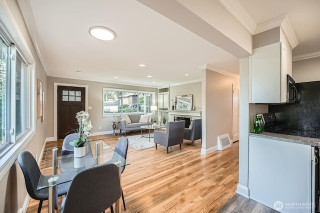 dining area with light wood-style floors, crown molding, baseboards, recessed lighting, and a fireplace