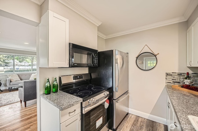 kitchen featuring stainless steel range with electric stovetop, black microwave, light wood-type flooring, crown molding, and white cabinets