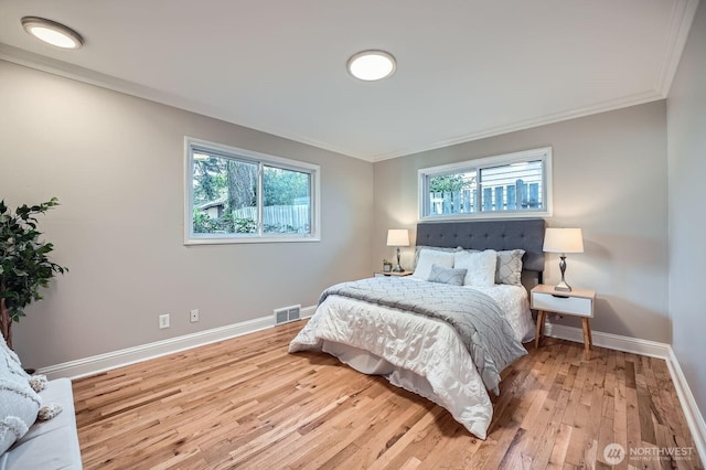 bedroom with ornamental molding, baseboards, and light wood-style floors