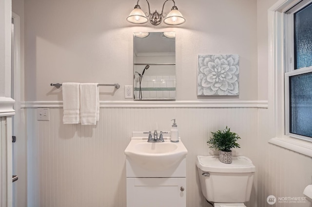 full bathroom with wainscoting, toilet, vanity, and a shower