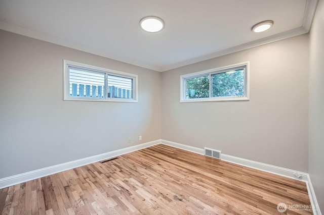spare room featuring baseboards, crown molding, and wood finished floors