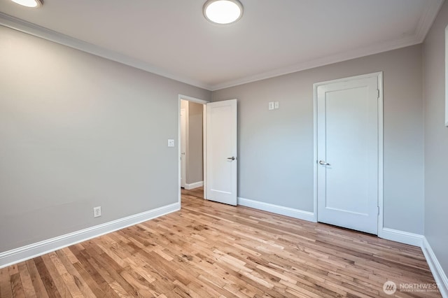 unfurnished bedroom with baseboards, light wood finished floors, and ornamental molding
