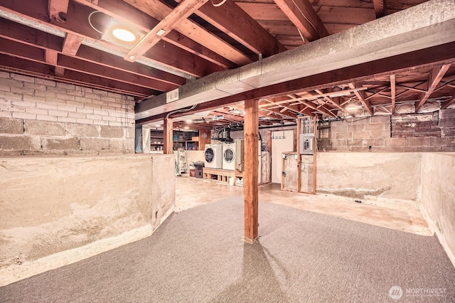 unfinished below grade area featuring independent washer and dryer and electric panel