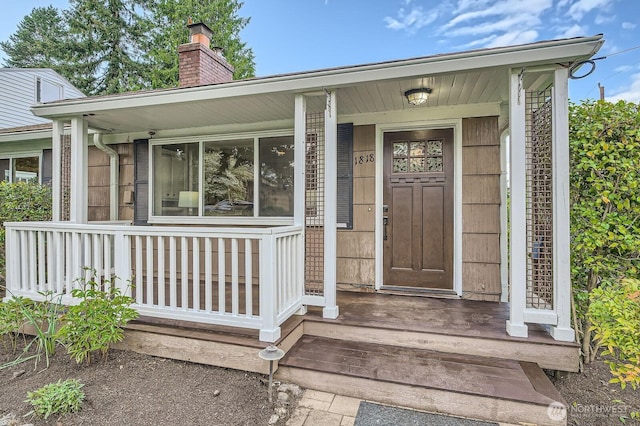entrance to property featuring a chimney and a porch