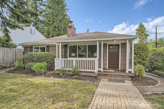view of front facade featuring covered porch, a chimney, and a shingled roof