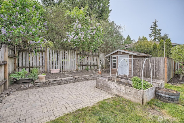 view of patio / terrace with a garden, a storage unit, a fenced backyard, and an outdoor structure