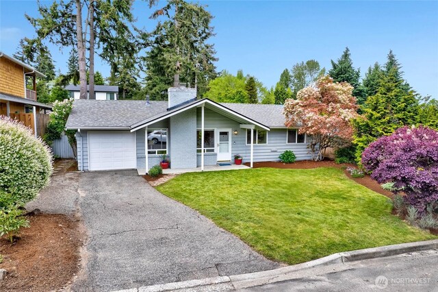 view of front of house featuring an attached garage, a chimney, asphalt driveway, a front yard, and roof with shingles