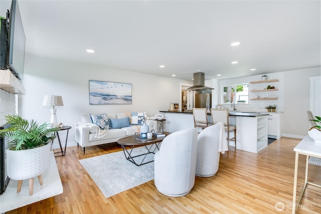 living area featuring light wood-style flooring, recessed lighting, and baseboards