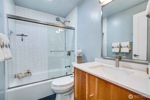 bathroom featuring toilet, enclosed tub / shower combo, and vanity