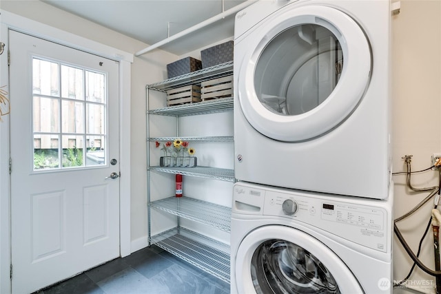clothes washing area with stacked washer and clothes dryer and dark tile patterned floors