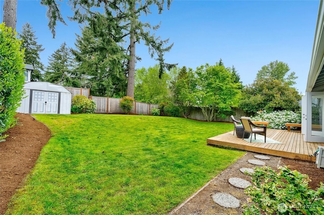 view of yard featuring a wooden deck, a storage unit, and an outdoor structure