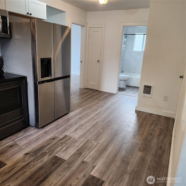 705 E 54th St, Tacoma, WA 98404 - kitchen with stainless steel appliances, white cabinetry, wood finished floors, and baseboards