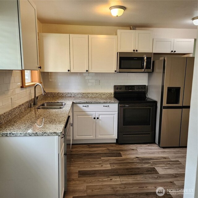 705 E 54th St, Tacoma, WA 98404 - kitchen featuring stainless steel appliances, a sink, white cabinets, light stone counters, and dark wood-type flooring