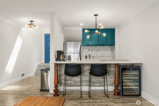 716 W Argand St Unit C, Seattle, WA 98119 - indoor wet bar with wine cooler, freestanding refrigerator, ornamental molding, wood finished floors, and tasteful backsplash