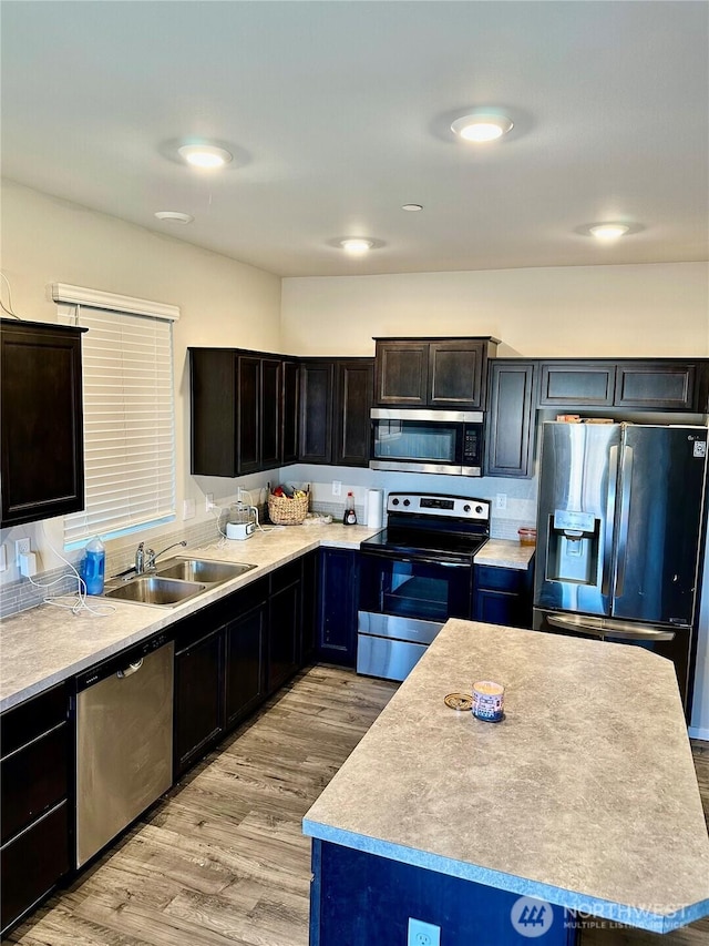 10823 187th Street Ct E, Puyallup, WA 98374 - kitchen featuring stainless steel appliances, a sink, light wood-type flooring, light countertops, and a kitchen island