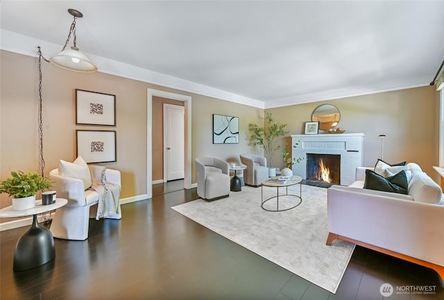 living area with a brick fireplace, ornamental molding, and baseboards