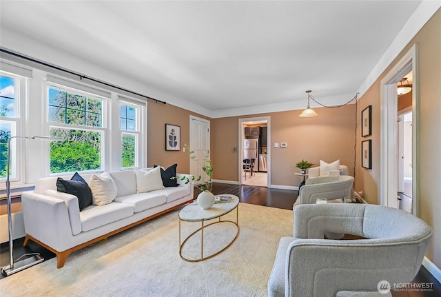 living area with plenty of natural light, baseboards, and wood finished floors
