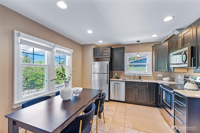 kitchen with appliances with stainless steel finishes, a sink, light countertops, recessed lighting, and hanging light fixtures