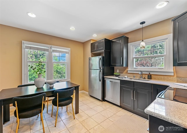 kitchen with appliances with stainless steel finishes, a sink, recessed lighting, decorative light fixtures, and light tile patterned flooring